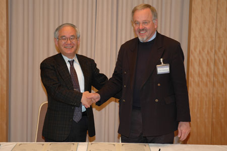 "Dr. Poerschke, Executive Manager of Springer, right, shakes hands with Dr. Yagi, MITS Director-General, after signing." Image
