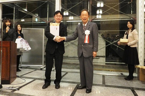 「表彰式で江崎 玲於奈 博士と握手する川添 直輝 MANA研究者」の画像