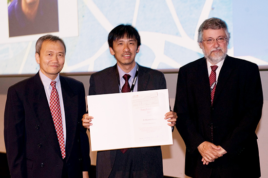 "Dr. Hayashi (center) receiving the IUPAP Young Scientist Prize, Professor Xiaofeng Jin (left, Commission Chair) and Professor Burkard Hillebrands (right, Commission Secretary)" Image