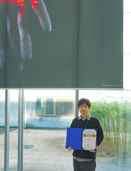 岩崎 拓哉 主任研究員と賞状の写真