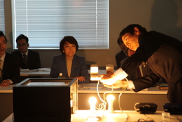 「世界中で使用されるLED用蛍光体の説明を受ける島尻大臣 (中央)」の画像